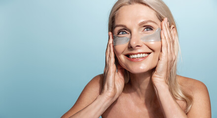 Smiling elderly woman with no blemishes, perfect skin, usng under eye patches from puffiness,...