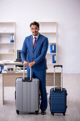 Young male employee preparing for trip at workplace