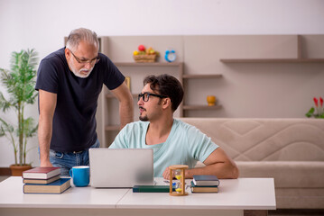 Young male student and his grandfather at home