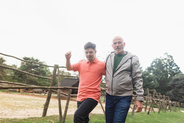 Happy senior father with his young son with Down syndrome walking in park together.