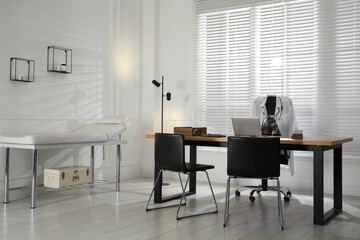 Modern medical office interior with doctor's workplace and examination table