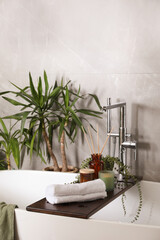 Modern white tub and beautiful green houseplants in bathroom. Interior design