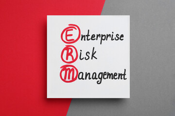 Paper with ERM abbreviation and its interpretation (Enterprise Risk Management) on color background, top view