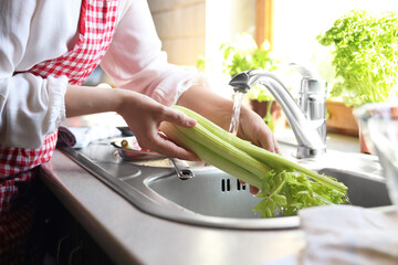 Woman washing fresh celery in kitchen sink, closeup - Powered by Adobe