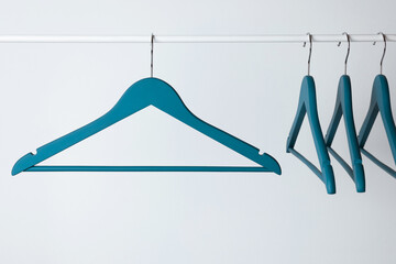 Blue clothes hangers on metal rail against light background