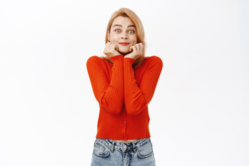 Excited young woman anticipating, looking at something with fascinated, admiring face expression, standing over white background