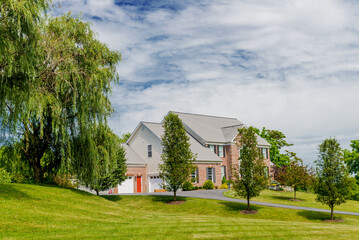 Fototapeta na wymiar Country modern mansion in traditional American style. large green lawn and trees.