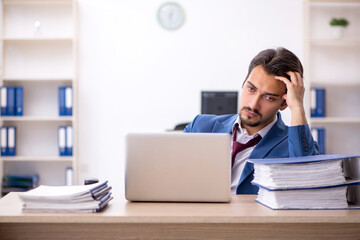 Young male employee unhappy with excessive work in the office