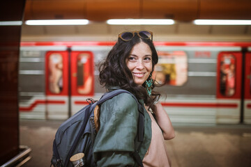 Mid adult woman commuter is standing in subway station and looking at camera.