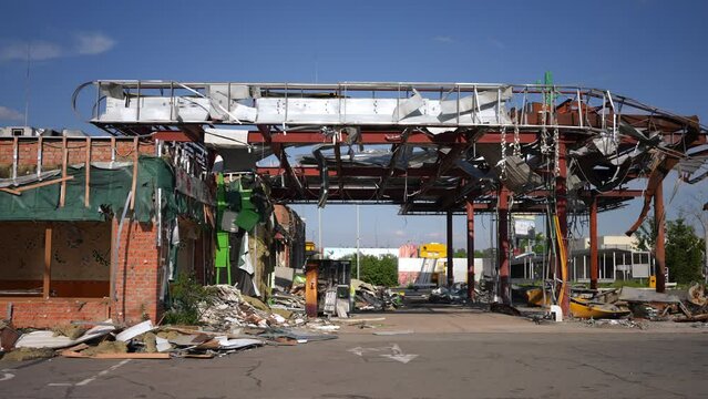 Side view ruined destroyed gas station in Kyiv Ukraine on summer day. Wide shot ruins of filling station in war zone outdoors. Bombing and destruction concept