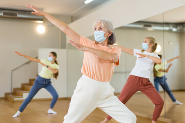 Fototapeta premium Family in protective masks are engaged in sports dancing in the gym