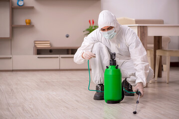 Young male contractor doing pest control at home