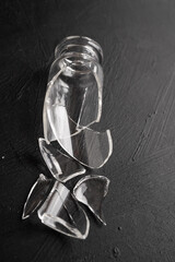 frasco de vidrio roto sobre fondo negro con textura, vidrio roto, pedazos de vidrio regados