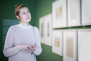 adult woman using smartphone and standing in art museum