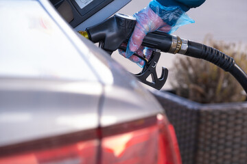  Refueling the car.Refueling pistol in the hands of a man in a blue glove.Car at a gas station. Silver car, refueling pistols and gloves.man fills up a car tank with diesel fuel. 