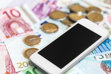 Blank screen smartphone which is placed on the pile of banknotes.