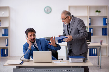 Old male boss and young male employee working in the office