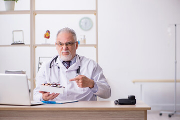 Old male doctor working in the clinic