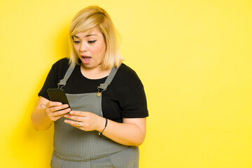 Surprised chubby woman with dyed blond hair looking at her smartphone in a studio