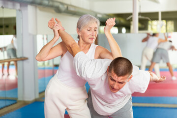 Mature woman self defense training gym learning to do painful grip