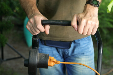 mowing the grass with an electric mower by a person