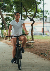 Obraz premium latina girl, smiling riding a bike in the park