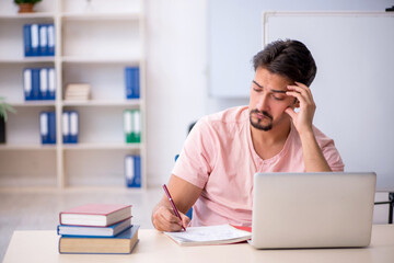 Young male student preparing for exams in the classroom