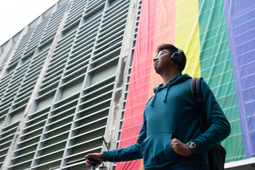 a proud young man looks to the horizon in the background of lgbt flag.