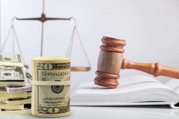 Law, auctioning, corruption, bankruptcy, judge gavel standing on sound block and bundle of dollars