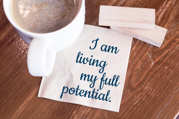 I am living my full potential positive affirmation - handwriting on a napkin with a cup of coffee
