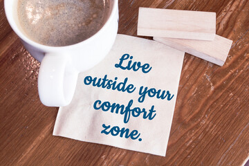 Live outside your comfort zone - inspirational handwriting on a napkin with a cup of coffee