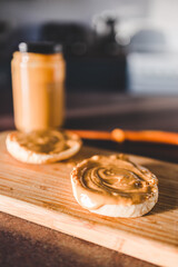Fototapeta na wymiar healthy plant-based food, peanut butter on freshly toasted English muffins for breakfast with kitchen bokeh