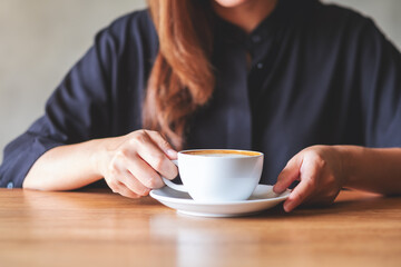 Closeup image of a woman holding a white cup of hot coffee