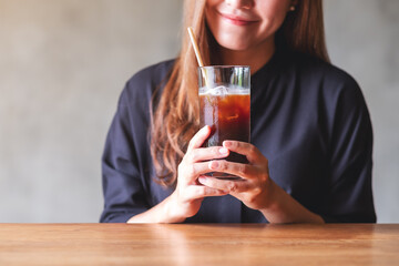 Closeup image of a beautiful young asian woman holding and drinking iced coffee