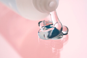 Hyaluronic gel or shower gel squeezed out of a bottle on a pink background.