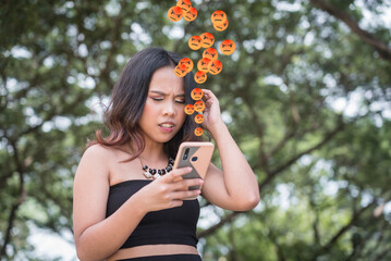 A worried young woman in a black top alarmed by a online bashing and harassment on her social media profile.