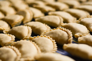 Close up of small uncooked creole traditional argentine salteñas empanadas ready to be baked. This typical food similar to pie is made with a flour-based dough and filled with different ingredientes.