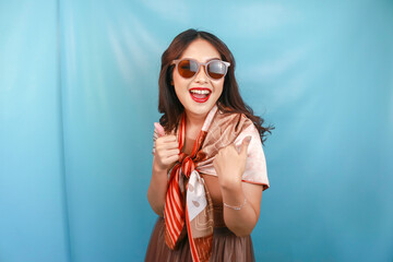 A young Asian woman traveler is smiling and showing a thumbs up gesture or OK sign.
