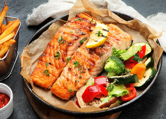 Salmon steak with vegetables on dark background.