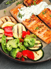 Salmon steak with vegetables on dark background.
