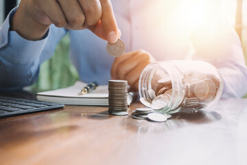 businessman holding coins putting in glass. concept saving money for finance accounting