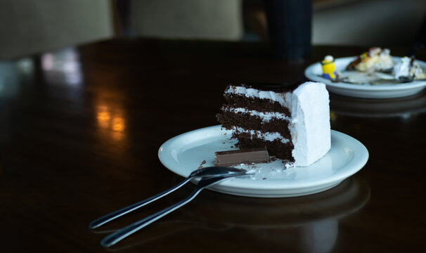 Chocolate Cake On White Plate With Wooden Table Background. Slice Cocoa Cake In Coffee Shop Restaurant. Snack Sweet Food Bekery  Pastry Relax In Holidays. Dessert Ingredient Cream Have Calories Food.