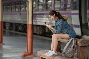 Beautiful asian woman tourist using smart phone and waiting train at train station, Travel and vacation concept