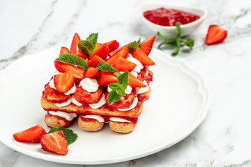 homemade tiramisu cake with fresh strawberry, mascarpone and mint. Tiramisu portion on plate on light background. Delicious no bake tiramisu