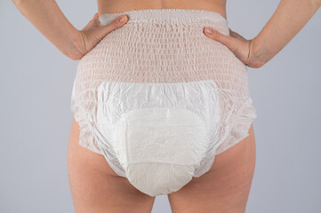 Rear view of a Woman in adult diapers on a white background. Incontinence problem.  - obrazy, fototapety, plakaty