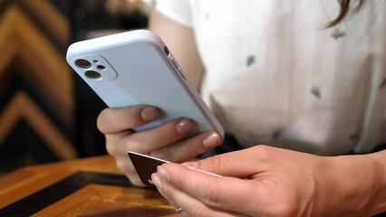A woman, holding a mobile phone in her hand, pays a bill, an order using an application.