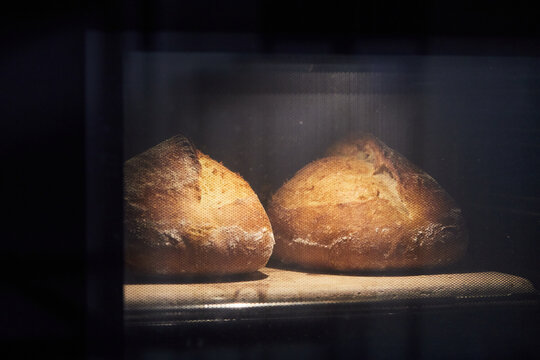 The process of making wheat bread at home. Baking bread in the oven. The concept of healthy homemade food. Front view.