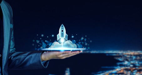 Startup business concept. Businessman holding a tablet, rocket launching and soar flying out from...