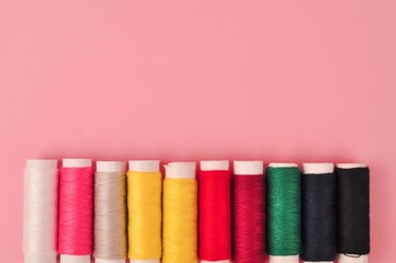 Multicolored threads for sewing on pink background