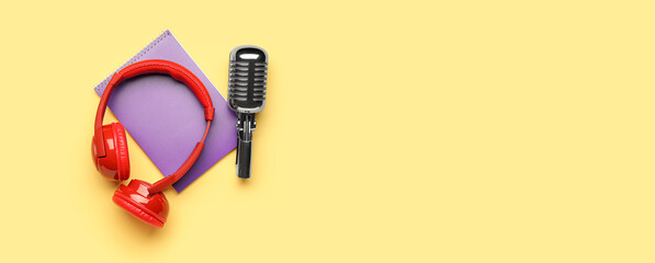 Headphones with microphone and notebook on yellow background with space for text